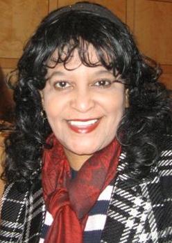 Woman with dark hair wearing red scarf and plaid jacket